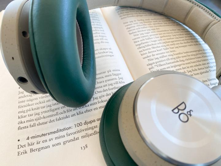 Ett par hörlurar av over-ear-typ ligger på en bok för att illustrera en ljudbok.