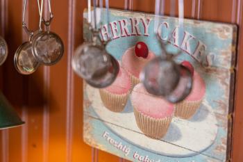 Vägg med en tavla i trä som det står cherry cakes på. Framför hänger tekulor.